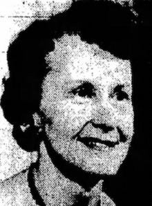 A smiling white woman of about sixty years, with short dark hair in a set style