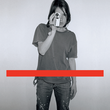 A black-and-white photo of a woman taking a photo with a red line.