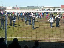 People in everyday clothing on football pitch