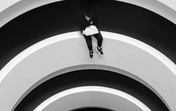 A man sitting on the edge of a circle reading a book