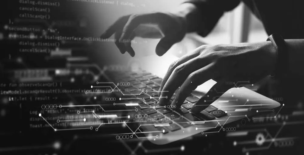 Close-up of hands typing on the laptop keyboard and a fade preview of a written code