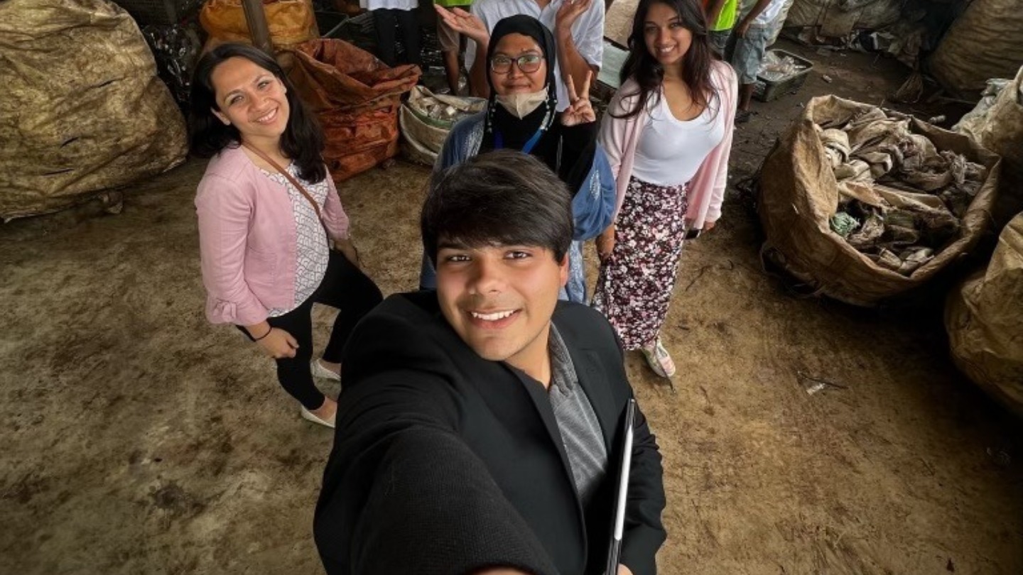 Students pose for a selfie in front of a plastics project.