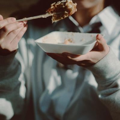 たこ焼きっぽいマヨついたものを食べ歩く女子の写真