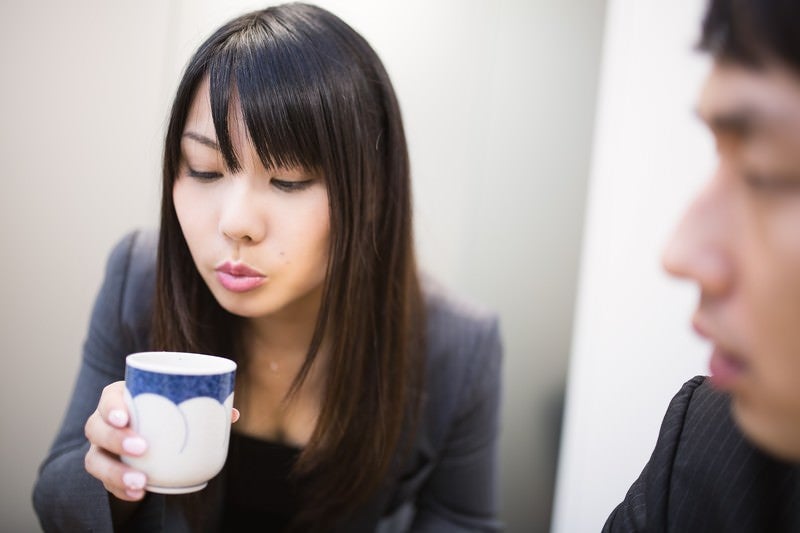 フーフーしてお茶を冷まし来客の胸を熱くする女性社員の写真