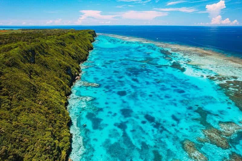 断崖絶壁の伊良部島三角点と宮古ブルーの海（空撮）の写真