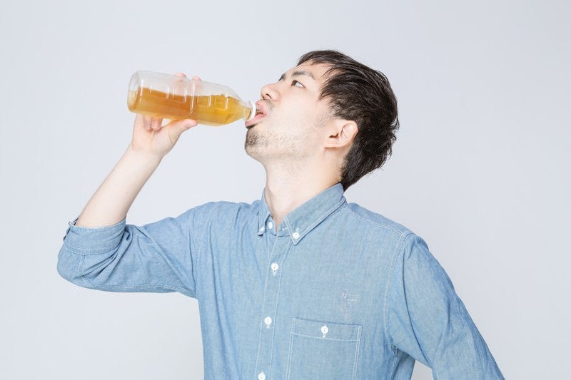 お茶をぐびぐび飲む男性の写真