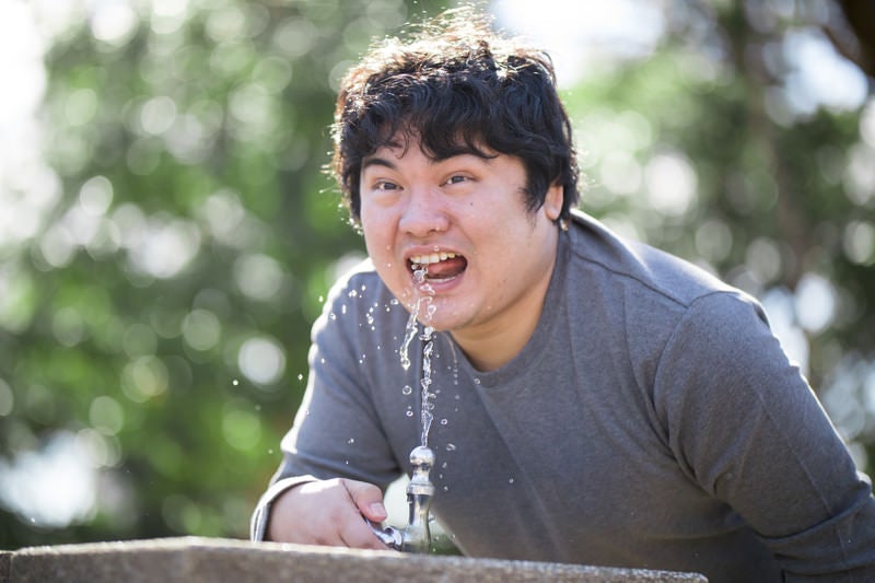 公園の水飲み場を使う男性の写真