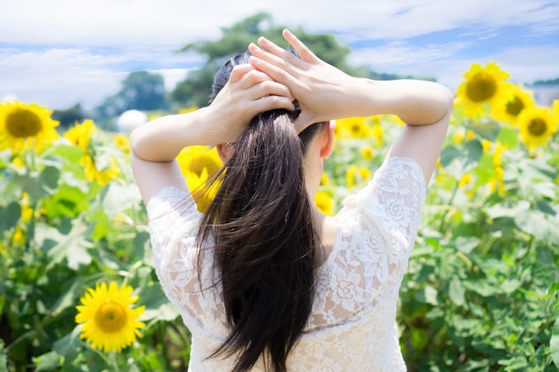 暑くて後ろに髪を束ねる女性の写真