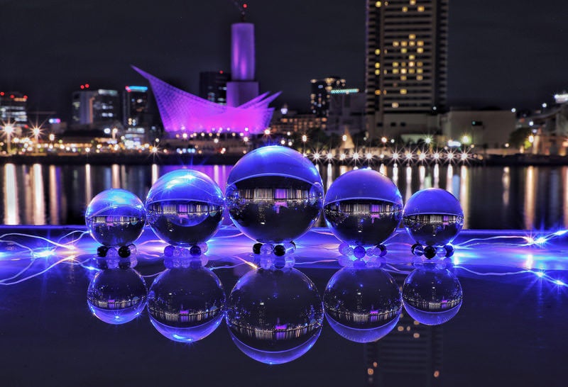 ライトアップされた夜景の前に並ぶ水晶玉の写真