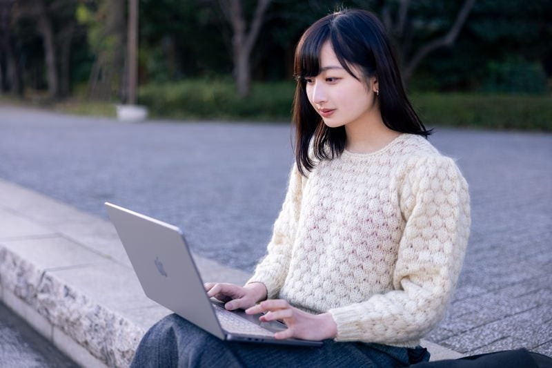 公園でネットサーフィンする女性の写真