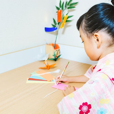 机の上で短冊に願いをこめる浴衣の女の子の写真