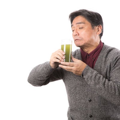 苦手な青汁をすすり飲むお父さんの写真