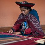 A woman at the Chinchero Weaving Collective works on a loom