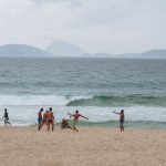 A group of guys juggling a soccer ball on Copacabana Beach