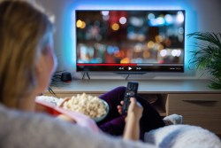 Woman relaxing at home in evening and watching TV