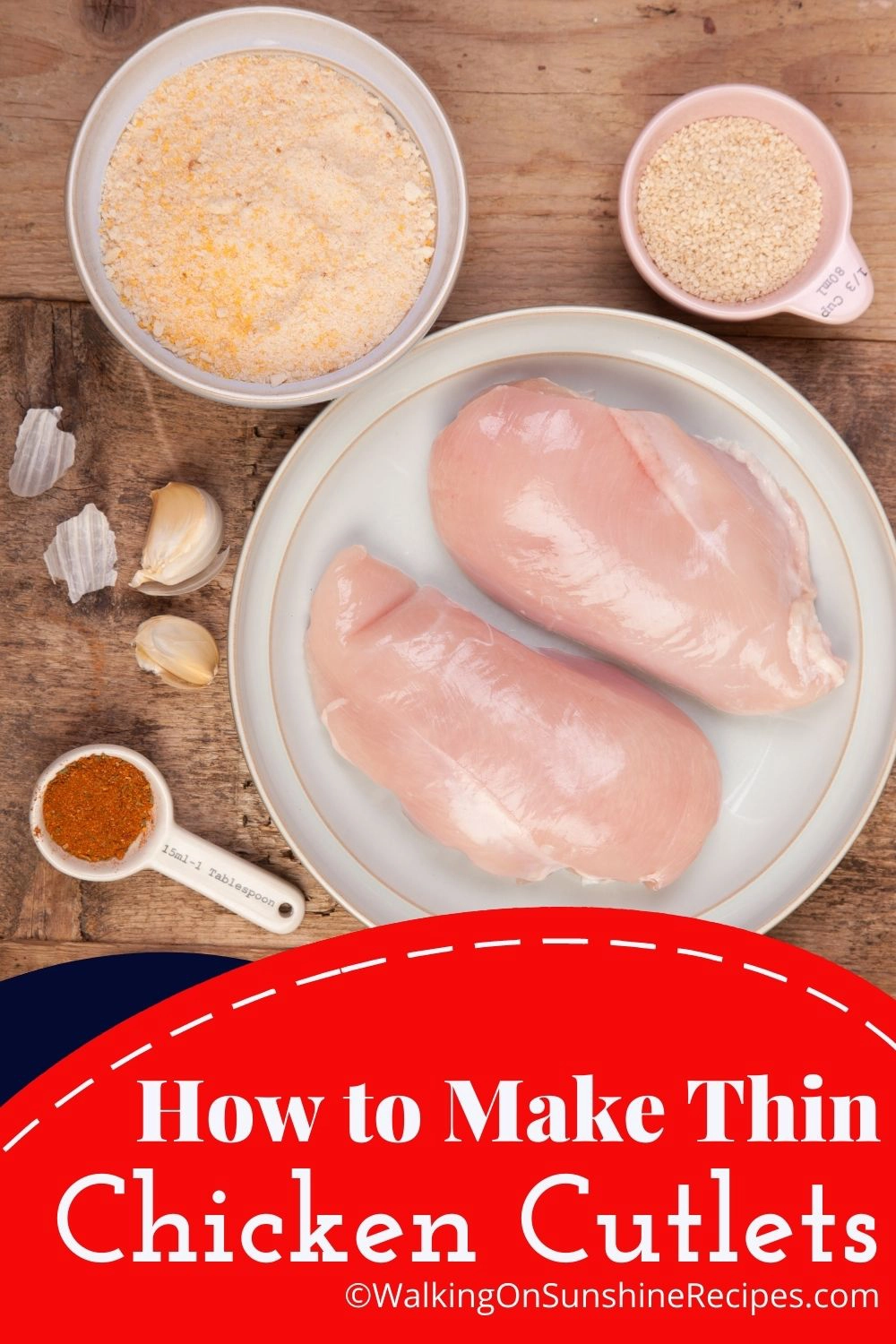 Chicken breasts on plate with breadcrumbs, garlic cloves and seasoning mix. 