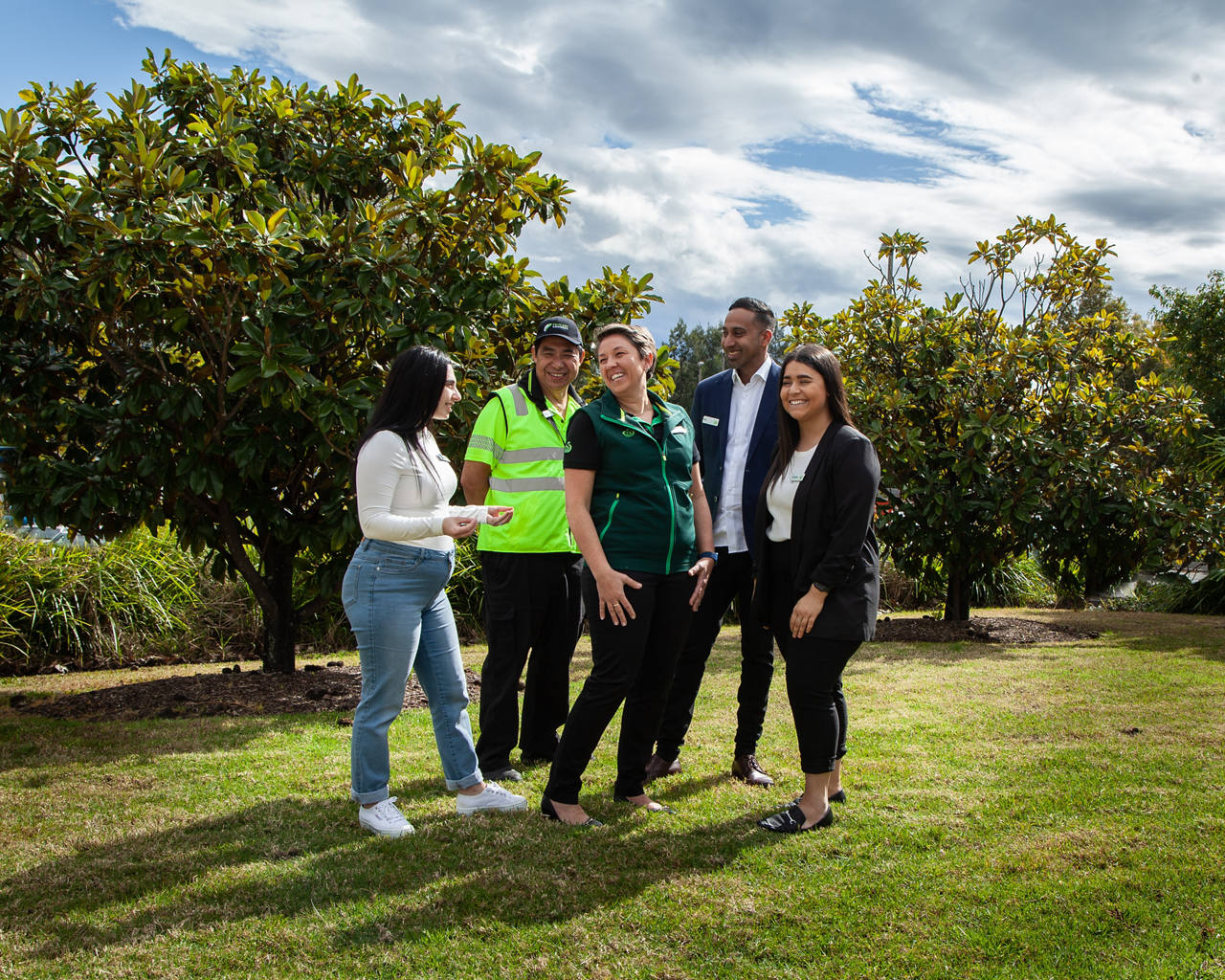 A group of employees from Woolworths Group smiling and standing together