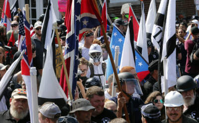 White nationalist demonstrators walk into the entrance of Lee Park surrounded by counter demonstrators on Aug. 12, 2017, in Charlottesville, Va. A federal judge on Dec. 30, 2022, has slashed millions of dollars from the damages a jury ordered white nationalist leaders and organizations to pay for their role in the violence that erupted during the deadly “Unite the Right” rally in Charlottesville in 2017. (AP Photo/Steve Helber, File)