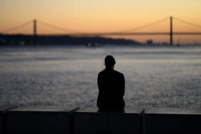 A woman watches the sun set. (Armando Franca/AP)