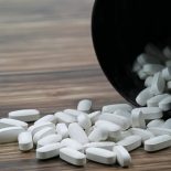 Article thumbnail: White pills spilling out of a toppled dark pill bottle on wooden ground, copy space.