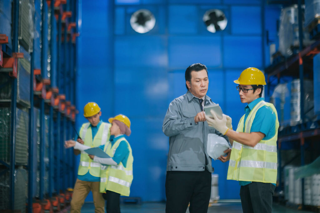 Two men in warehouse discussing information on a tablet