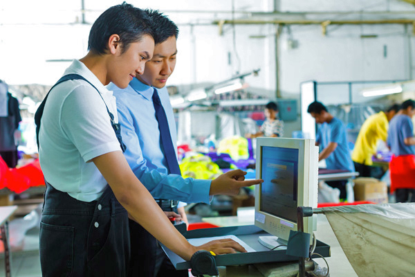 Worker and boss discussing something on computer screen in a factory