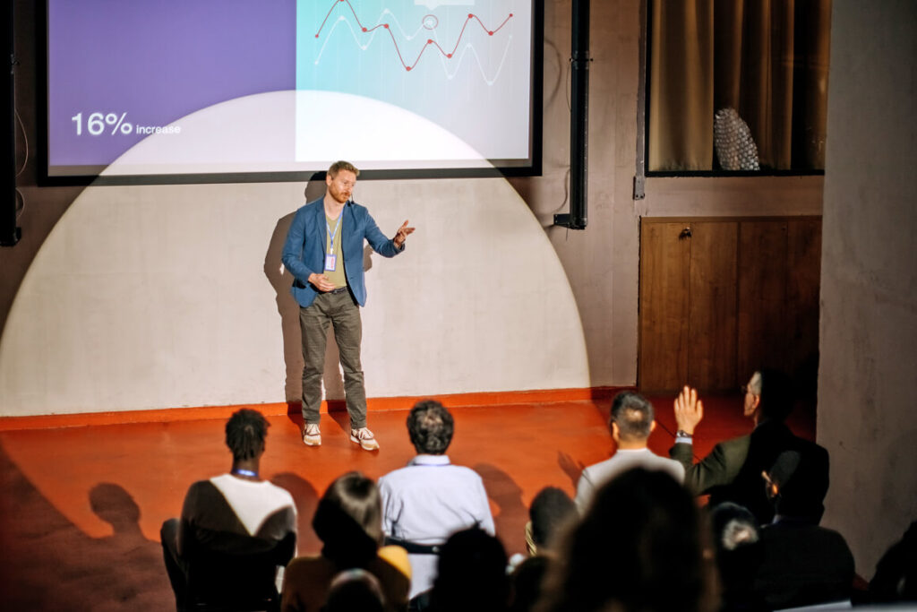 Man on stage speaking to audience