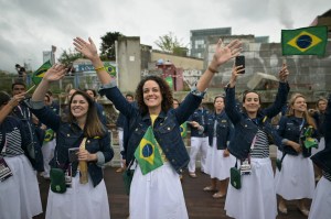 Members from Brazil's delegation greet other boats as they sail in a boat along the river Seine