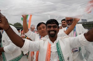 Members of Team India cover themselves from the rain on a boat on the River Seine