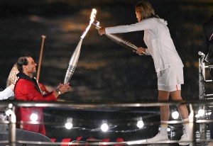 Spain's tennis player Rafael Nadal hands over the Olympics torch to former French tennis player Amelie Mauresmo holding the torch during the opening ceremony of the Paris 2024 Olympic Games