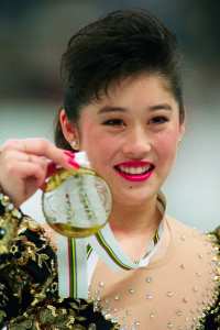 Kristi Yamaguchi from the United States smiles as she displays her gold medal on the podium of the women's figure skating event at the Winter Olympic Games 21 February 1992 in Albertville. Japanese Midori Ito won the silver medal and Nancy Kerrigan, from the United States, the bronze.