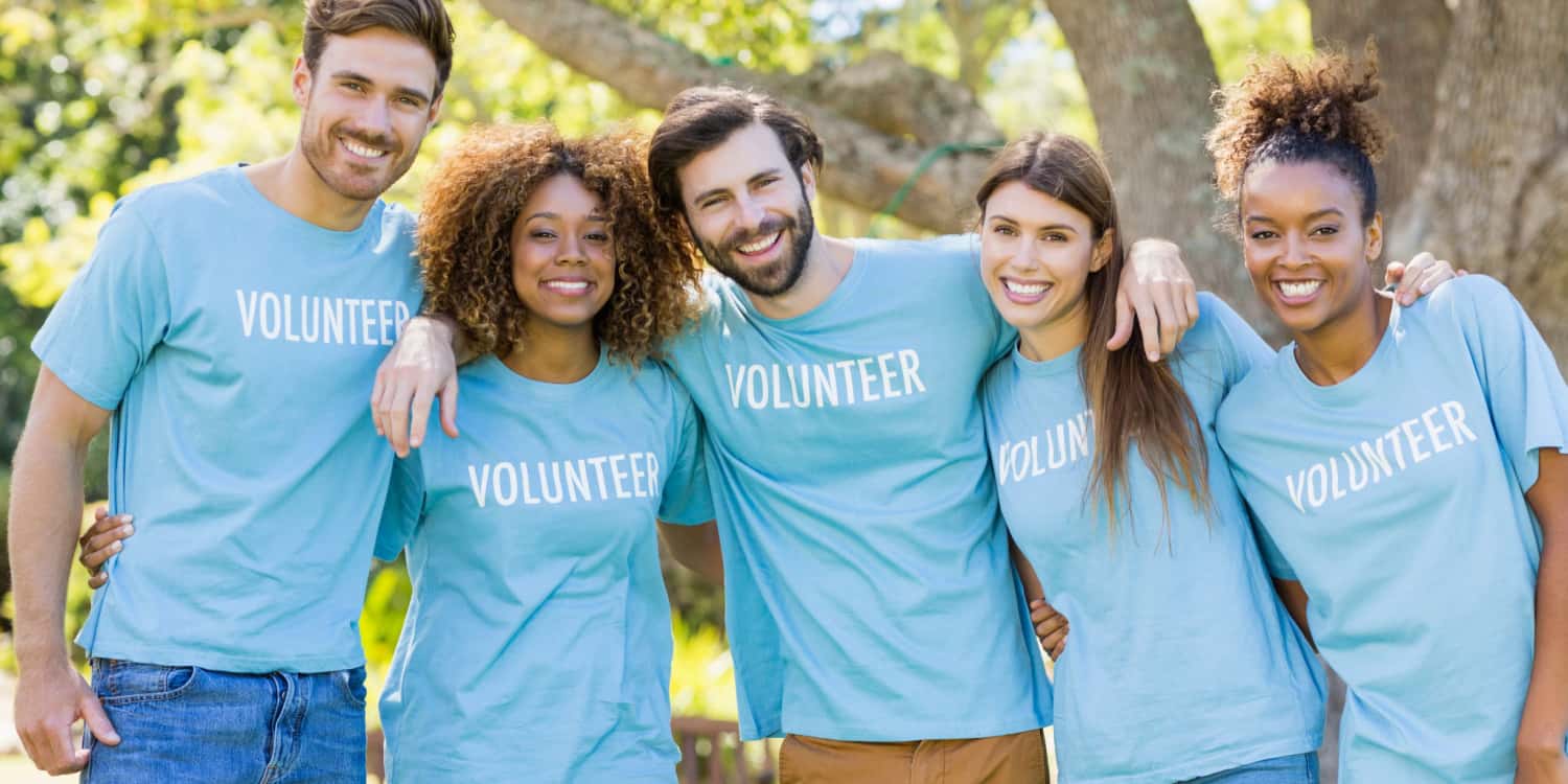 Portait of a volunterr group posing in a park.