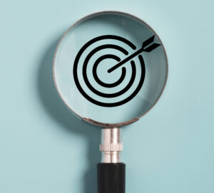 Target board inside of magnifier glass for focus business objective on blue background and copy space.