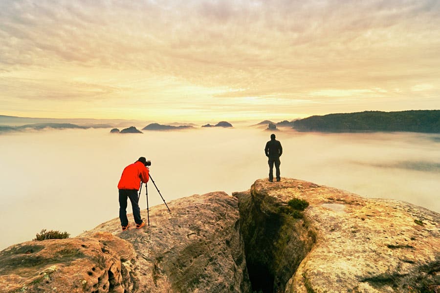 Photographer and his apprentice shooting on top of mountain