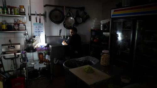 FILE - Las Palmas Cafe employees work with power from a generator during an island-wide blackout in San Juan, Puerto Rico, April 7, 2022. (AP Photo/Carlos Giusti, File)