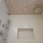 Subway tile shower walls with mosaic accents.