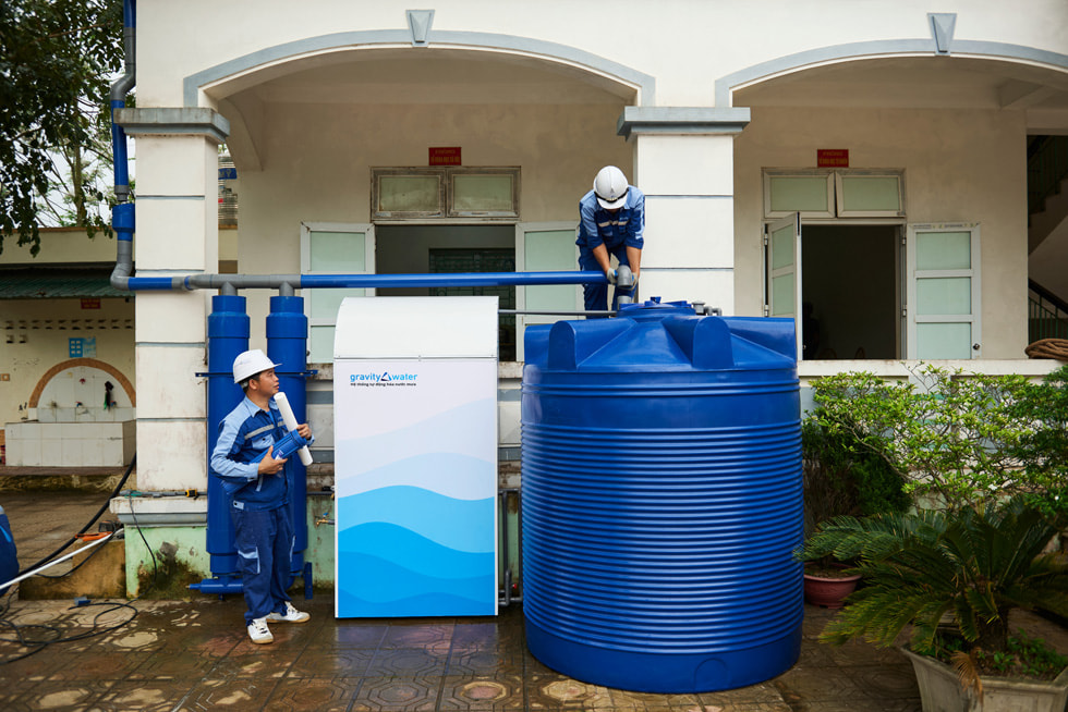 Ein Teammitglied inspiziert das Gravity Water System, während der Kollege ihn beobacht.
