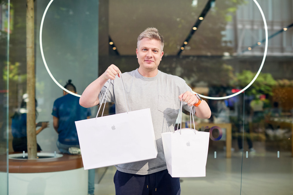 Un cliente sostiene dos bolsas de Apple con sus compras.