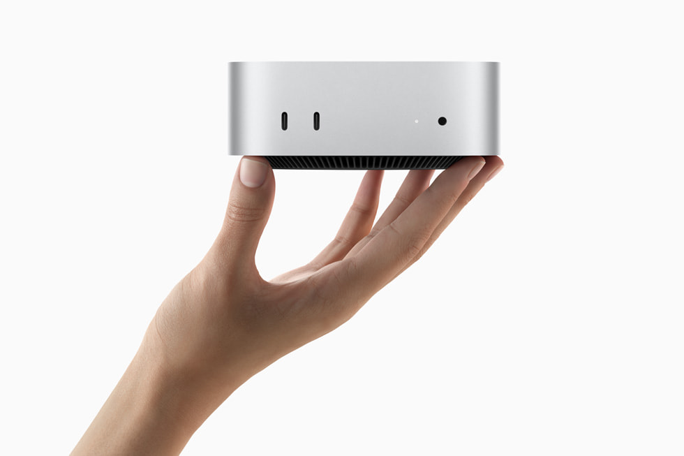 A hand holds the all-new Mac mini.