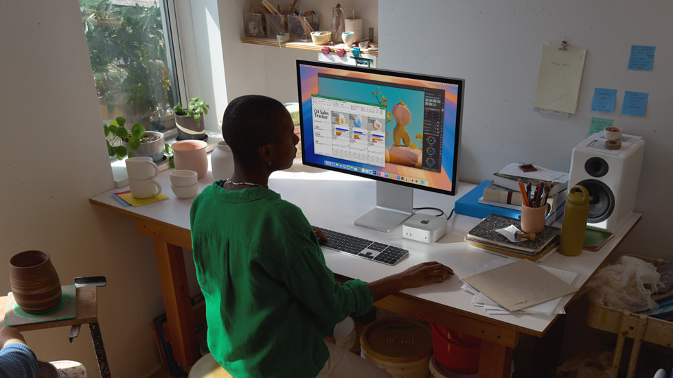 A Mac mini user works at a desk surrounded by ceramics pieces.