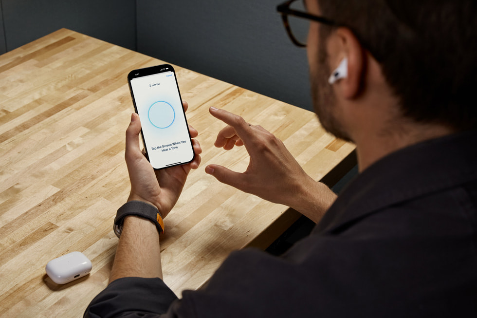 An AirPods Pro 2 user holds iPhone while using the new Hearing Test feature.