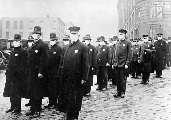 Policemen line a street with masked faces.