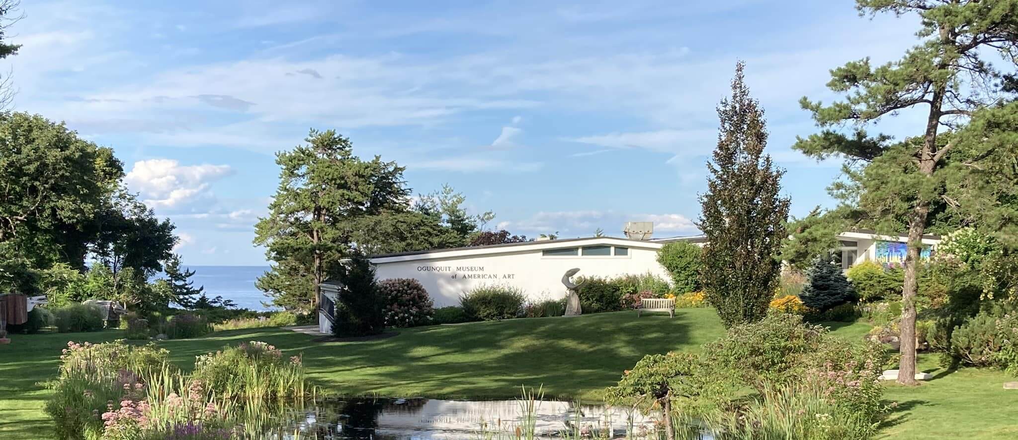 building nestled in green forest with ocean in background