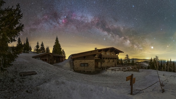 Die Sommermilchstraße geht an einem Wintermorgen über dem Lusenschutzhaus im Nationalpark Bayerischer Wald auf, fotografiert von Patrick Leitner. Im Winter 2018/2019 war Jupiter dort zu finden - das besonders helle Licht am Horizont rechts der Milchstraße. | Bild: Patrick Leitner