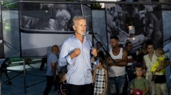 A man in a blue shirt speaking into a microphone.