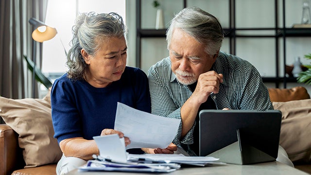 Retired Asian couple looking at bills