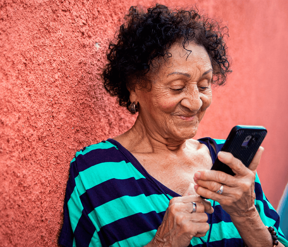 Uma senhora feliz mexendo no celular.