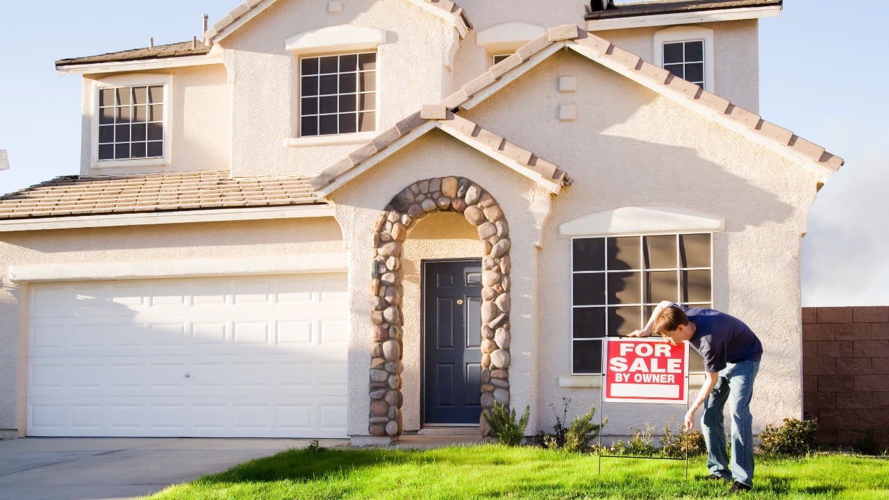 Home seller putting a for sale sign in yard