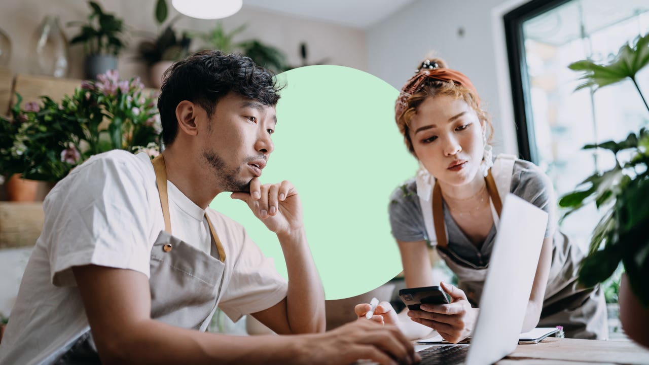 An Asian man and woman review a laptop.