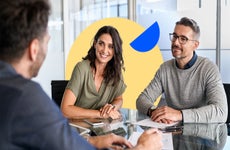 A man and woman discuss loan details with a bank advisor.